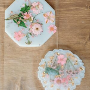 Top view of handmade epoxy resin decor with pink flowers on a wooden table. Perfect for elegant home styling.